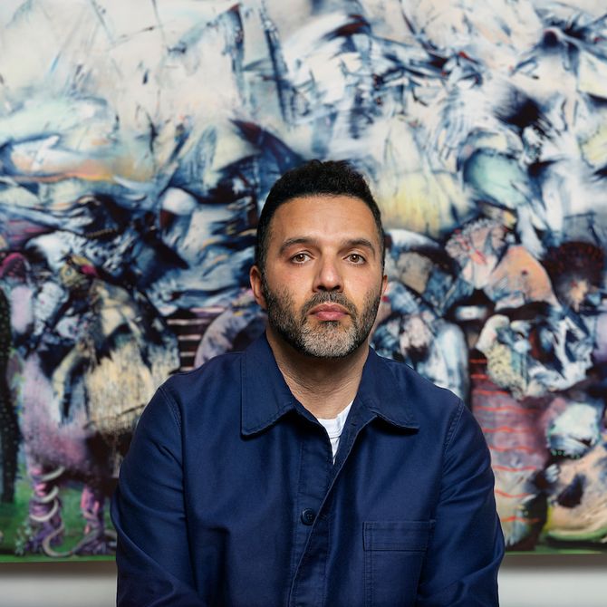 Ali Banisadr sat in front of a colourful painting