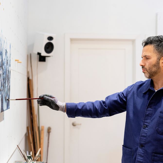 Ali Banisadr stood back and adding detail to a painting on a wall before him