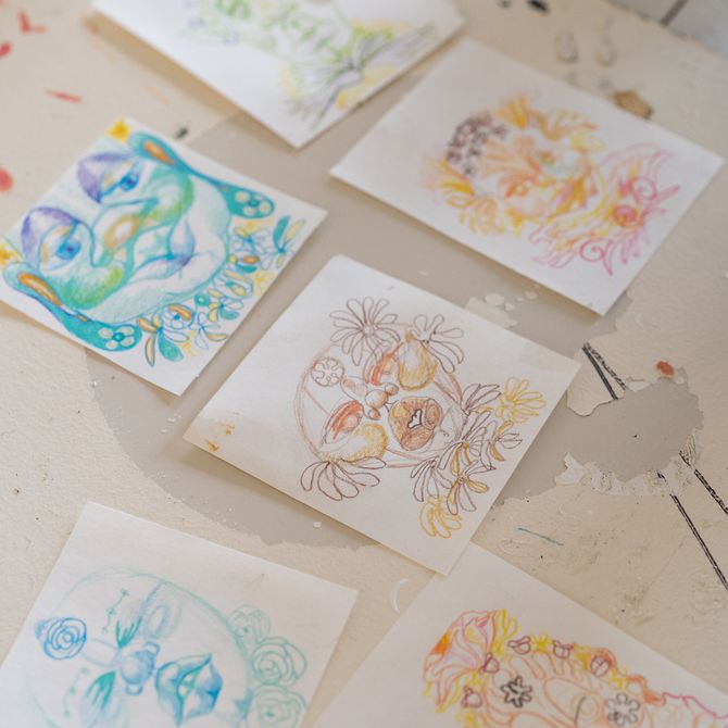 six pieces of square white paper with coloured pencil sketches of faces on