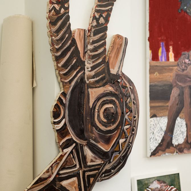 a painted head of an animal with antlers hanging on the wall in the artist's studio