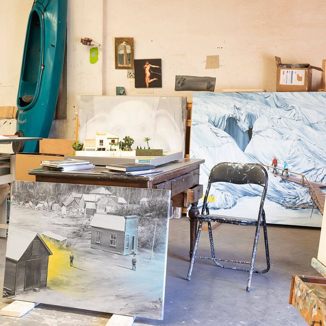 Artist's studio with a canoe propped against a wall, tables, chairs and a variety of finished paintings