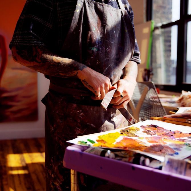 Caleb Hahne's working in his studio loft with paintings in the background