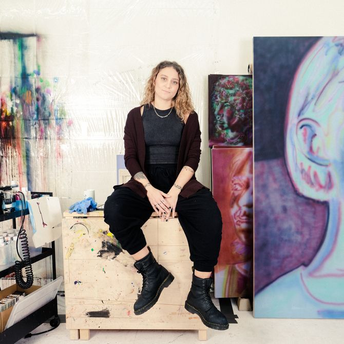Katie Hector sits in her studio on wooden block 