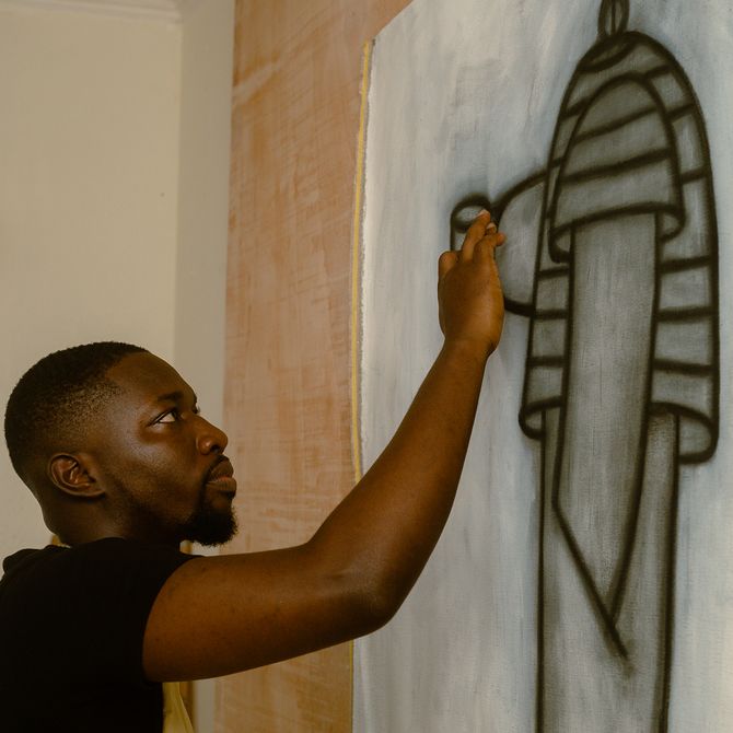 Kpe Innocent working on a drawing in his studio