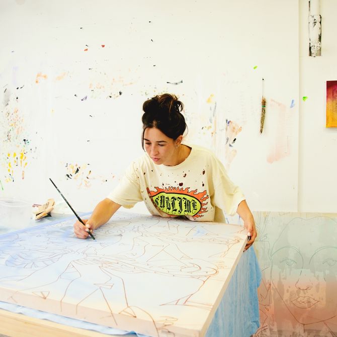 Marcela painting a canvas laid on a desk