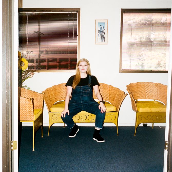 Sarah Zucker sits on yellow couch in her studio