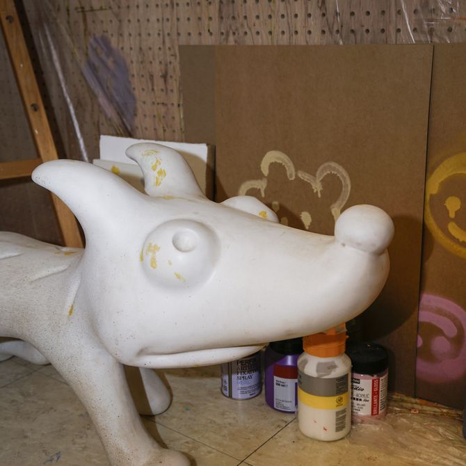 A white sculpture of a dog with exaggerated features on the floor in the studio