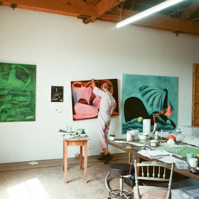 Tahnee hangs pink canvas on studio wall 