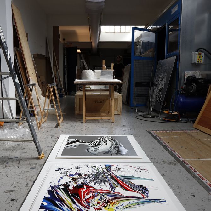 two large paintings placed alongside one another on a white plinth on the floor of the artist's studio