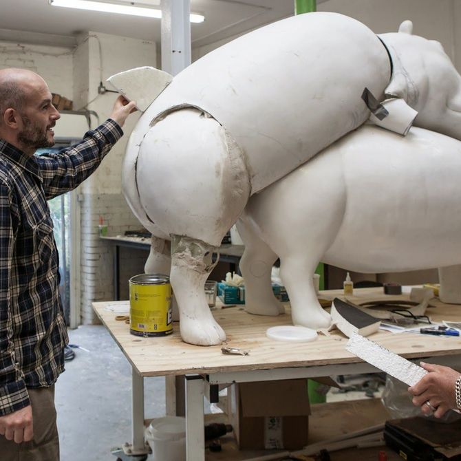 Jake and Dinos Chapman focusing on a sculpture on a desk in their studio