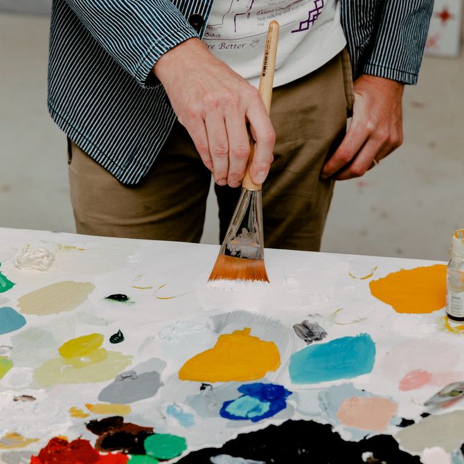 Ryan Travis Christian holding a paintbrush to a paint palette 