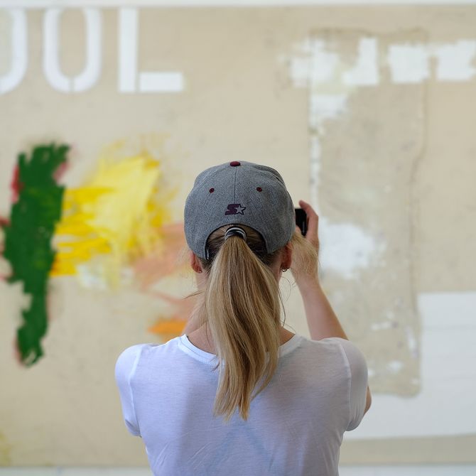 Jenny Brosinski taking a photograph of her artwork to which she faces