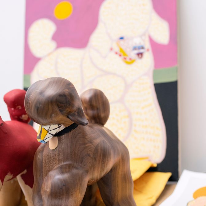 sculpture of poodle in front of larger painting of pink poodle