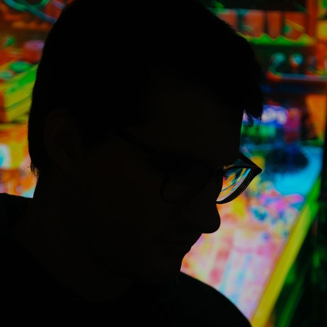 profile of NessGraphics in front of a digitally-displayed artwork