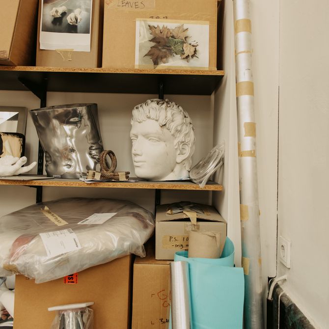 set of shelves in with various cardboard boxes and packages on it as well as a sculptural bust