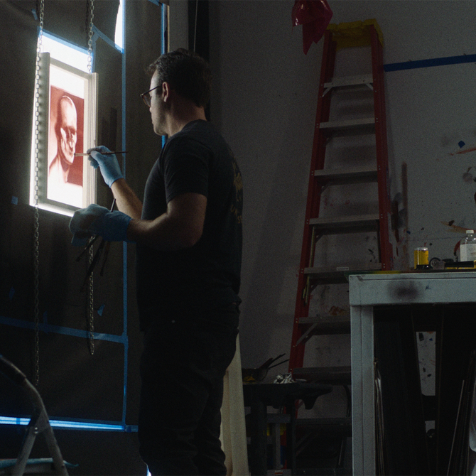 artist standing and hand finishing monoprint at the studio