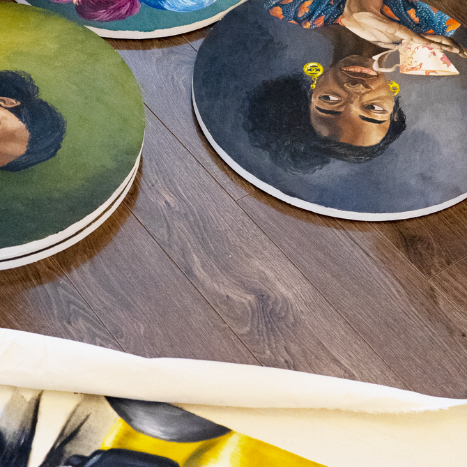 three different tondo portrait paintings on a wooden surface