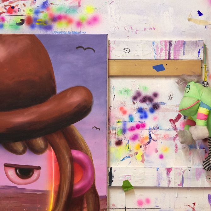 close-up of a section of a cowboy painting with paint splattered on the wall behind it and a frog hanging alongside it