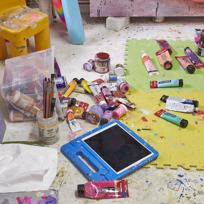 floor of the artist's studio with various tubes and pots of paint randomly dispersed along with a palette and some brushes