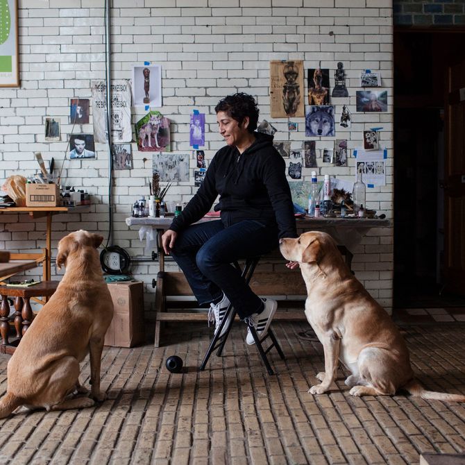Huma Bhabha sat in her studio smiling with her two dogs
