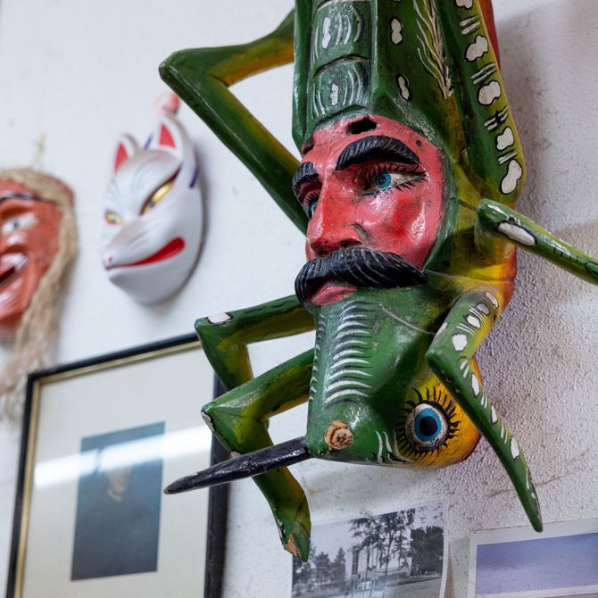 insect and mask hanging on a wall of the artist's studio