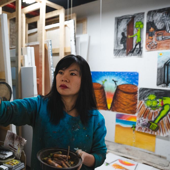 Hein Koh focusing on a pastel drawing in her studio