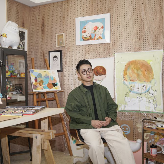 Lin-Yen Liang sits in his studio surrounded by his artwork on the walls