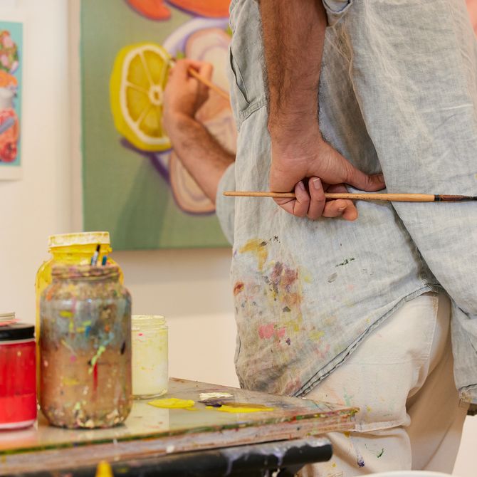 Pedro standing next to a table, painting a canvas