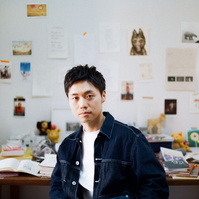 Chen Wei Ting sat in his studio in front of a desk and images taped to the wall