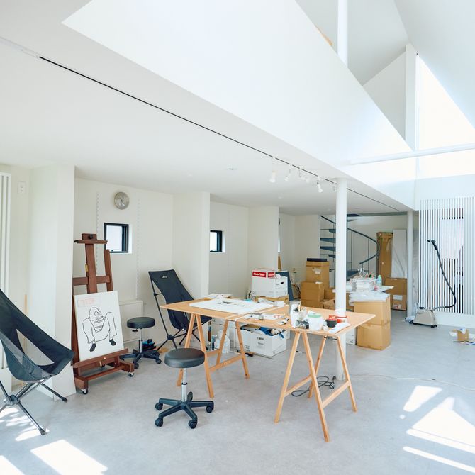 a bright and light studio space with various chairs, surfaces and artworks