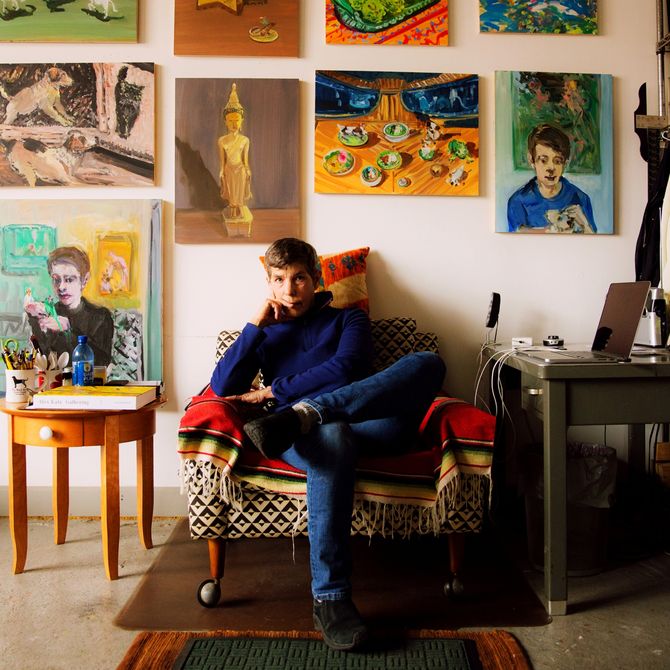 Deborah Brown sitting in an armchair surrounded by her paintings 