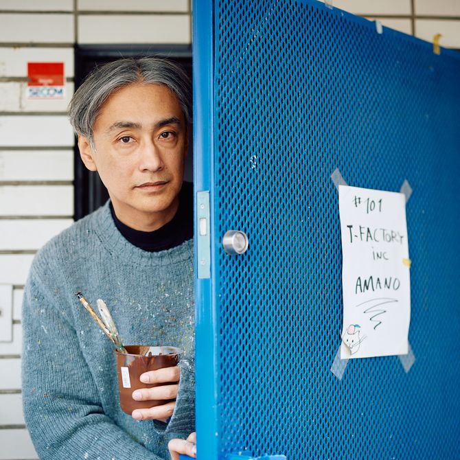 an artist opening the blue door to his studio while holding a brown paint pot