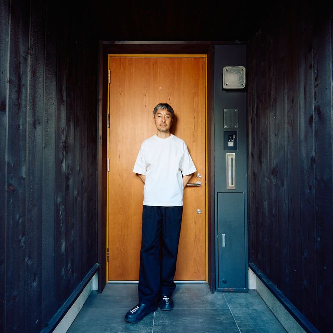 Yu Nagaba standing against the wooden doorway outside his studio
