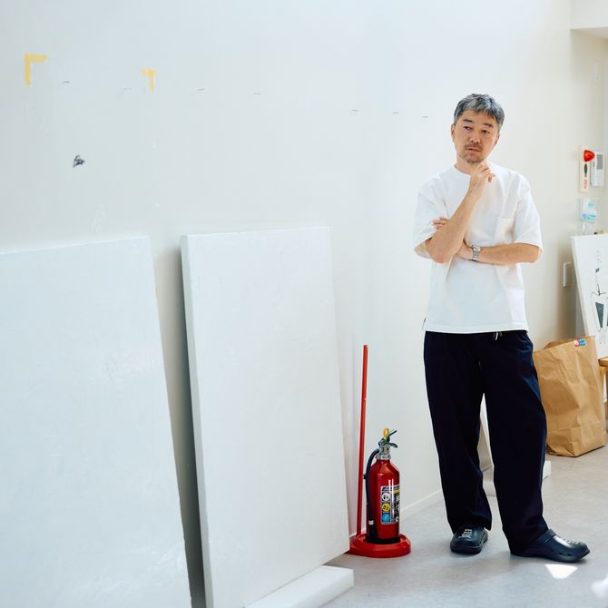 Yu Nagaba standing in his studio next to two blank canvases