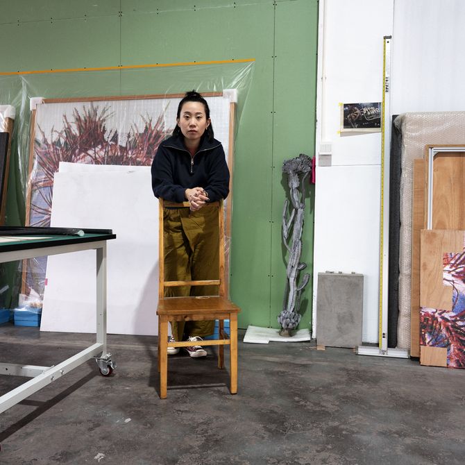Zhang Ruyi leaning forwards onto a chair in her studio