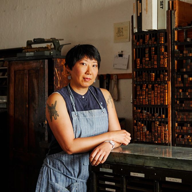 Christine Wong Yap leaning on a cabinet in her studio with her arms crossed over