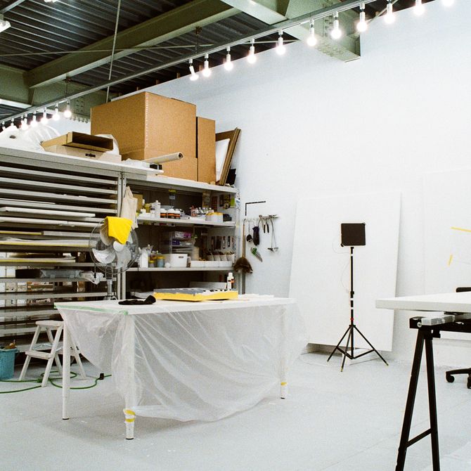 a bright white artist's studio with various shelves for canvases
