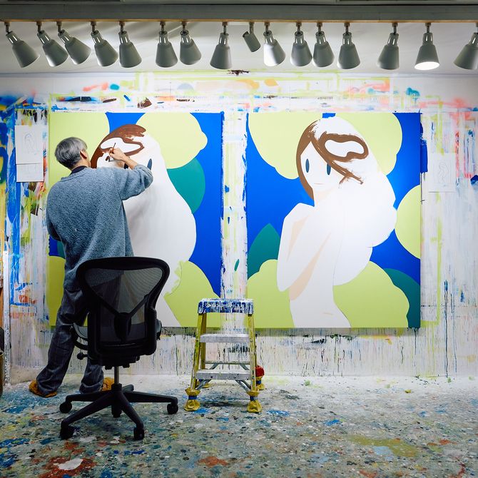 an artist painting in his studio on two large colourful canvases