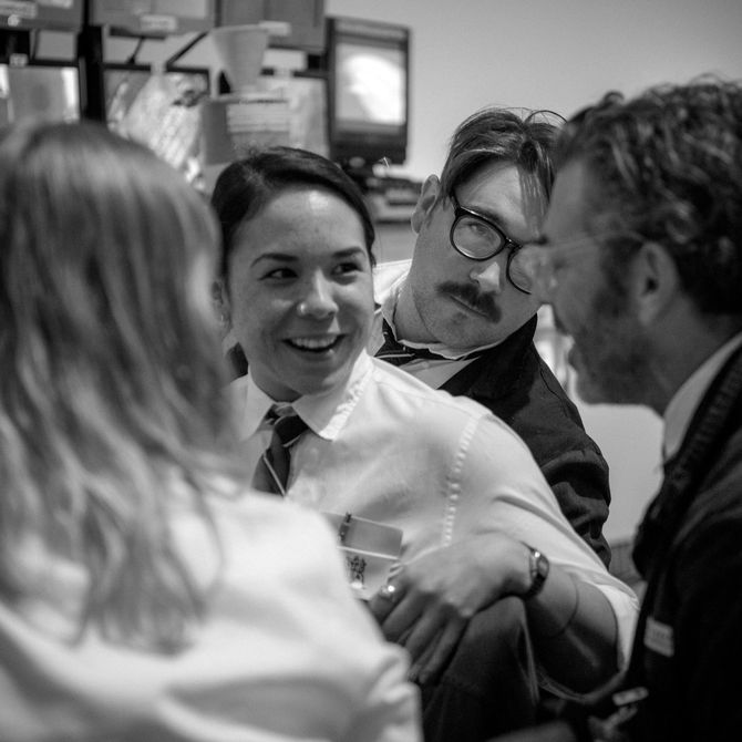 a black and white photograph of four smartly dressed people interacting