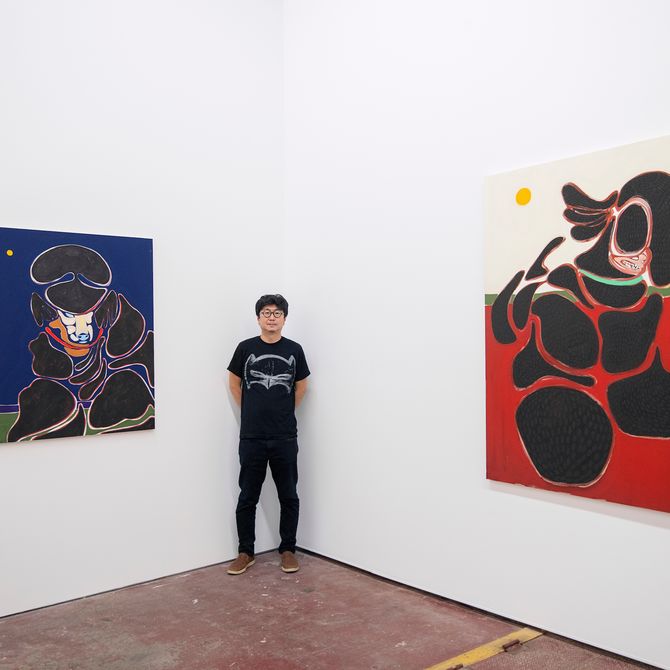 artist stood between two poodle paintings
