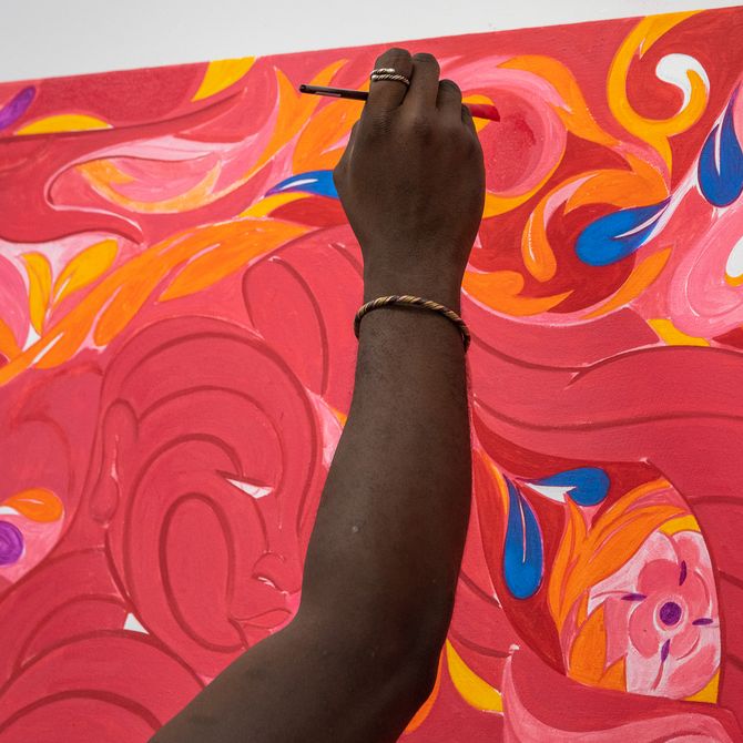 artist reaching up with a paintbrush towards a red canvas