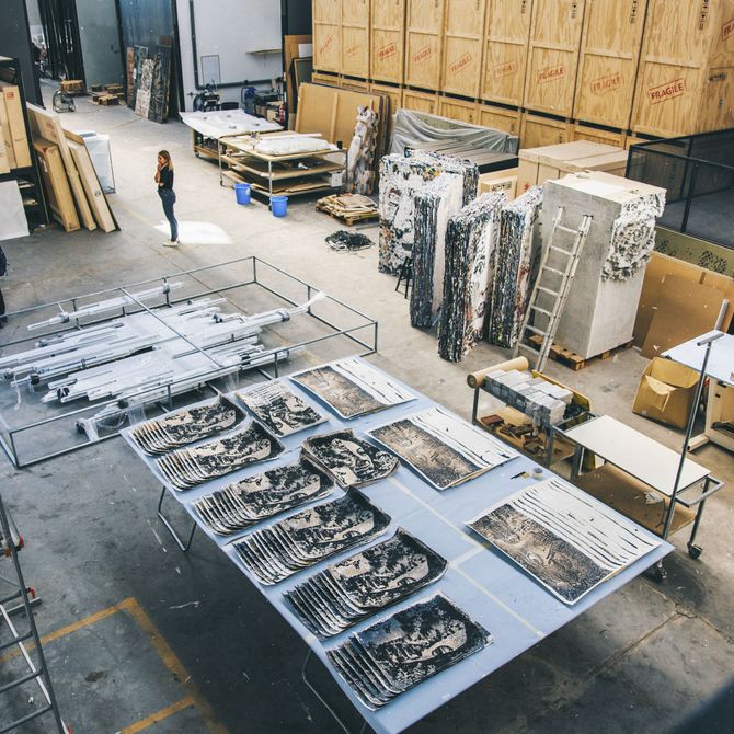looking down on studio floor filled with various storage containers and boxes, works of art and tools