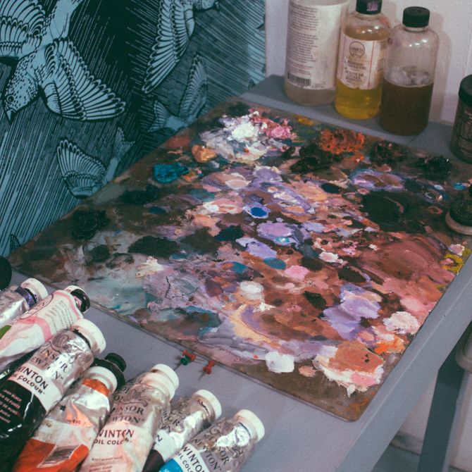 large paint palette on a table next to various tubes of oil paints