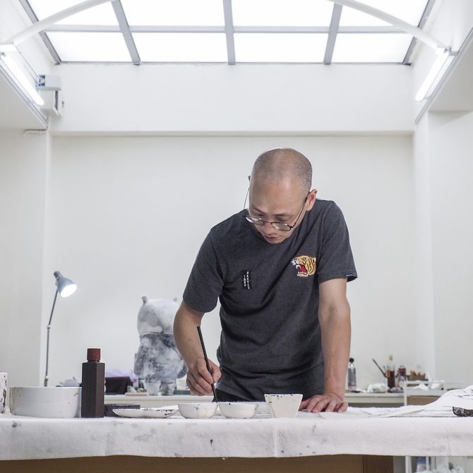 Artist A-Lei stood behind a desk in his studio