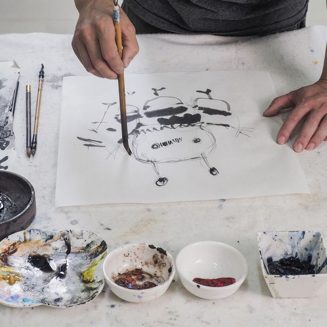 A-Lei working on a black ink drawing in his studio