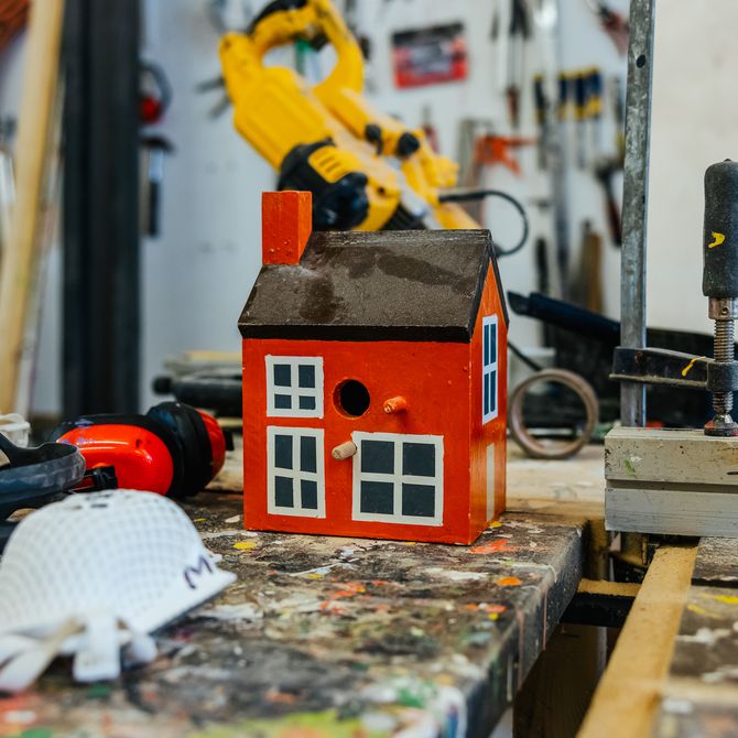 A small sculpture of a red house on a studio desk
