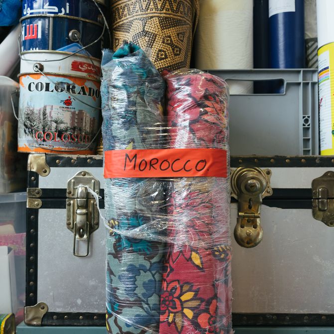 two rolls of patterned cloth wrapped up with cling film and a slip of paper that has 'Morocco' written onto it