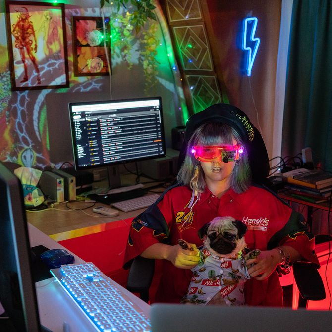 artist sitting behind a desk with multiple screens and holding a pug