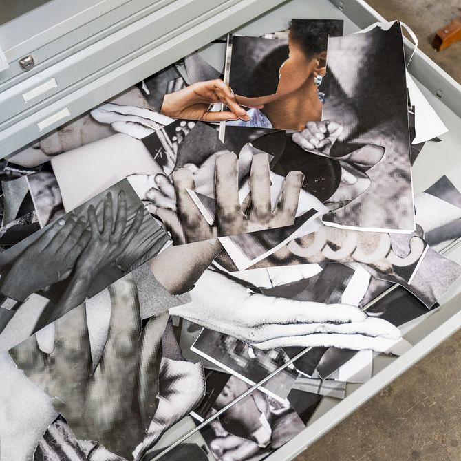 numerous monochrome photographic clippings and images, mainly of human hands, piled on top of one another