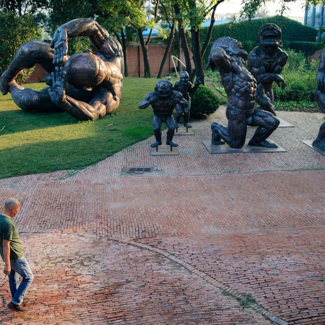 Yue Minjun walking into a garden of giant sculptures